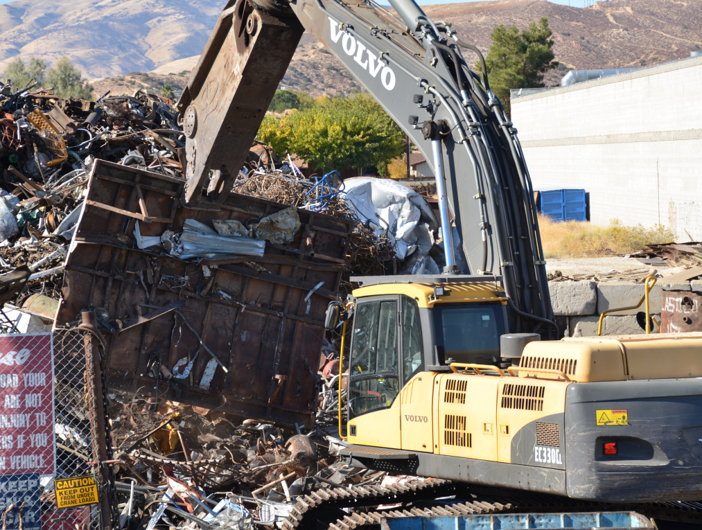 Photo of large machine moving scrap metal into a pile, linking to photo album.