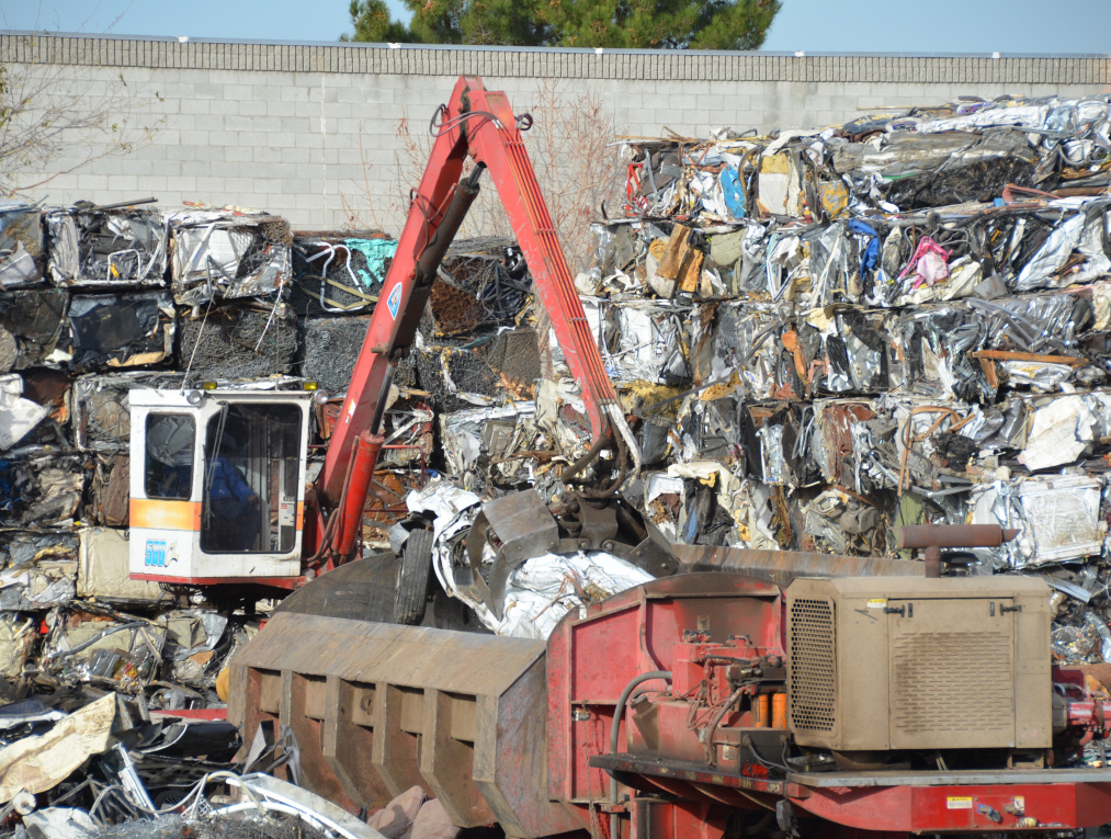 Photo of mechanical claw moving compressed scrap metal cubes onto stacked cubes, linking to photo album.