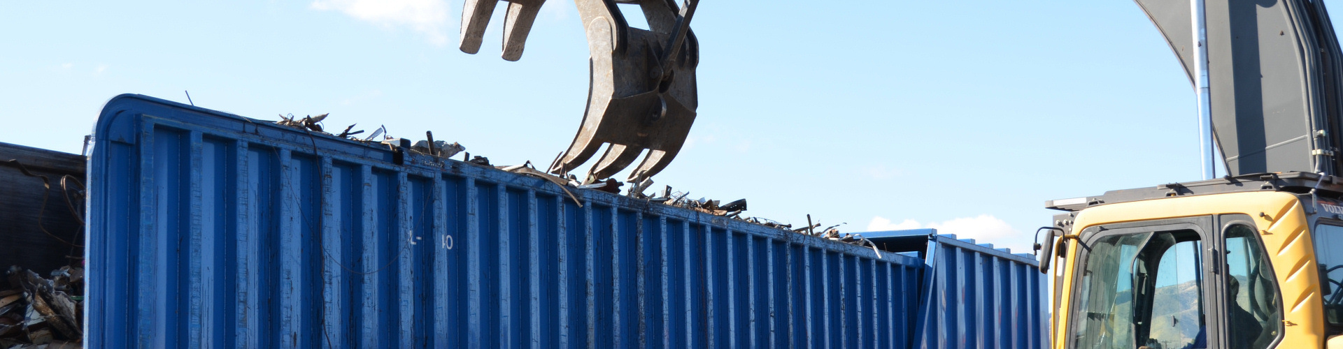 Photo of mechanical claw removing scrap metal from truck trailer.
