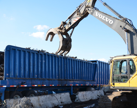 Photo of mechanical claw removing scrap metal from truck trailer.