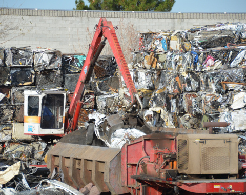 Photo of mechanical claw stacking comressed scrap metal cubes.